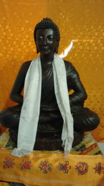 Siyah Gautam Buddha heykeli, boynundaki beyaz bezle sessizce oturuyor.