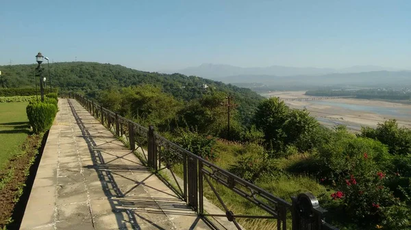 Nehrin ve dağların güzel doğa manzarası. Bir tatil köyünün bahçesinde yeşil ağaçlar var.