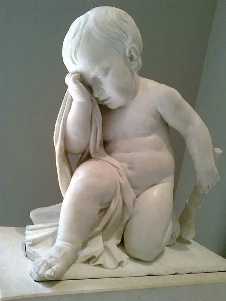 Beautiful stone statue inside Louvre museum of a small child