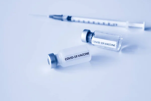Beyaz arka planda izole edilmiş Covid-19 aşısı şişesi ve 1 ml plastik şırınga.