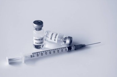 Beyaz arka planda izole edilmiş Covid-19 aşısı şişesi ve 1 ml plastik şırınga.