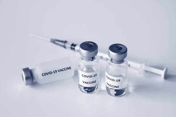 Beyaz arka planda izole edilmiş Covid-19 aşısı şişesi ve 1 ml plastik şırınga.