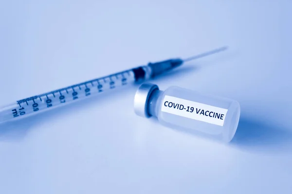 Beyaz arka planda izole edilmiş Covid-19 aşısı şişesi ve 1 ml plastik şırınga.