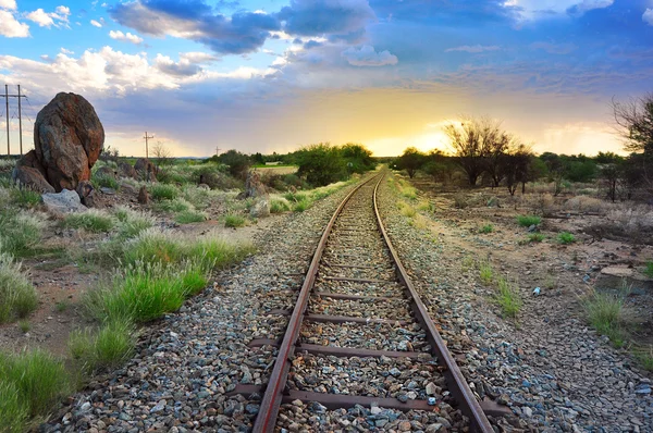 Oude spoorlijnen door Afrikaanse halve woestijn landschap en dramatische hemel Stockfoto