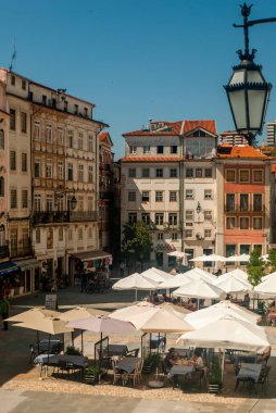 Coimbra Ticaret Meydanı 'nda güneşli bir öğle yemeği saatinde restoran masaları ve şemsiyelerle Portekiz, Coimbra, Vetical, Seçici Odaklanma