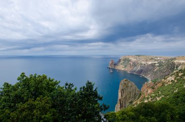 Denizin üzerinde bulutlu bir gökyüzü ile kıyı kayalıklardan 