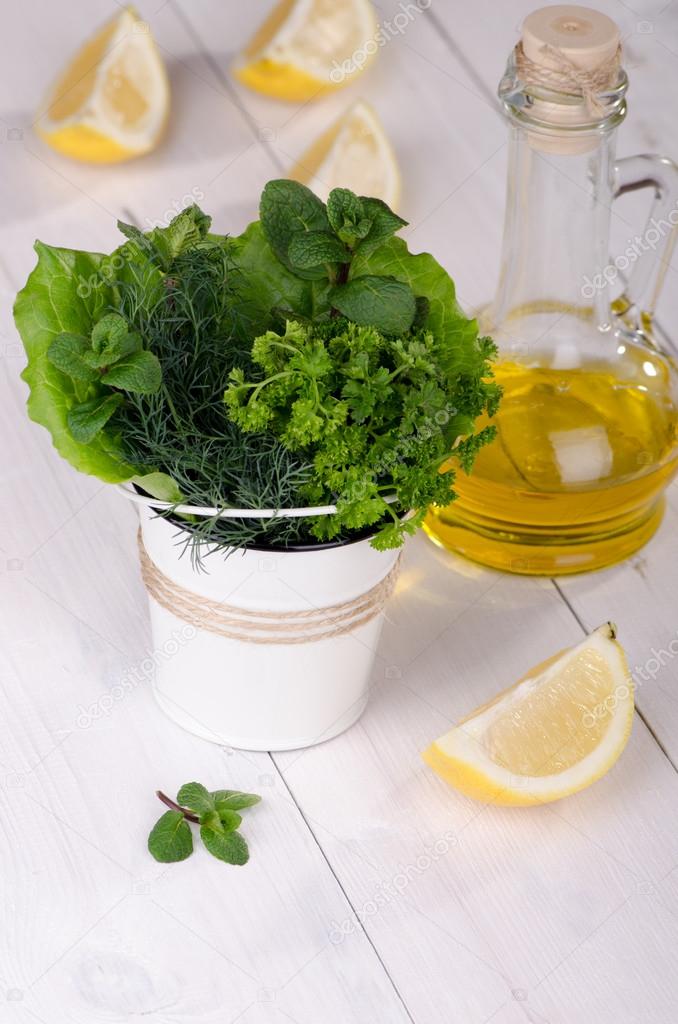 Fresh herbs in a bucket with lemon and olive oil 