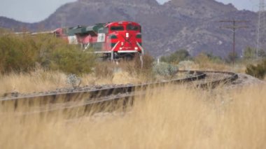 Tren raylarında bir tren, arkasında da dağ.