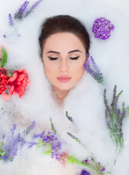 Femme avec des fleurs dans le bain de mousse — Photo