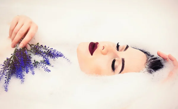 Femme avec des fleurs dans le bain de mousse — Photo
