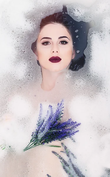 Femme avec des fleurs dans le bain de mousse — Photo