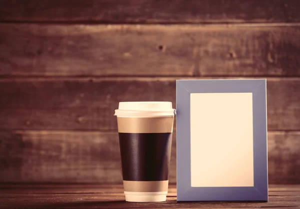 Cup en foto frame op de tabel — Stockfoto