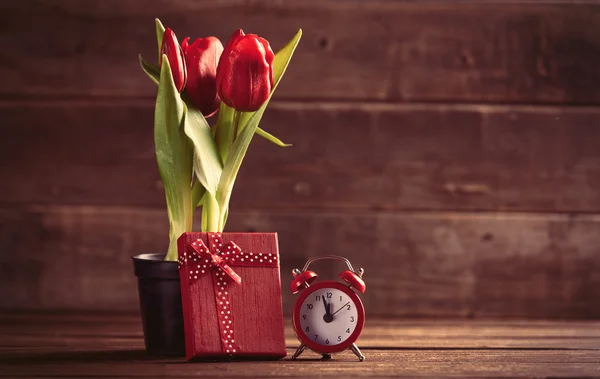 Bouquet de tulipes, cadeau et horloge sur la table — Photo