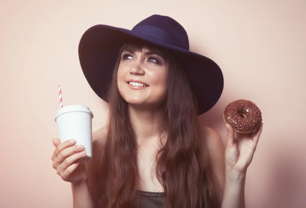 Молодая женщина с напитком и пончиком — стоковое фото