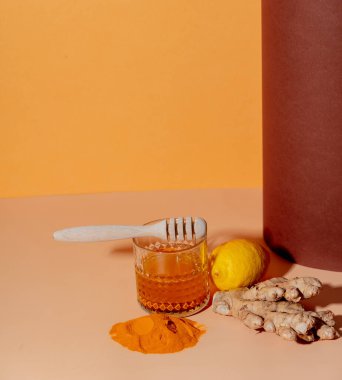 Zerdeçal, bal, limon ve zencefil kağıt arka planda bir bardağın yanında