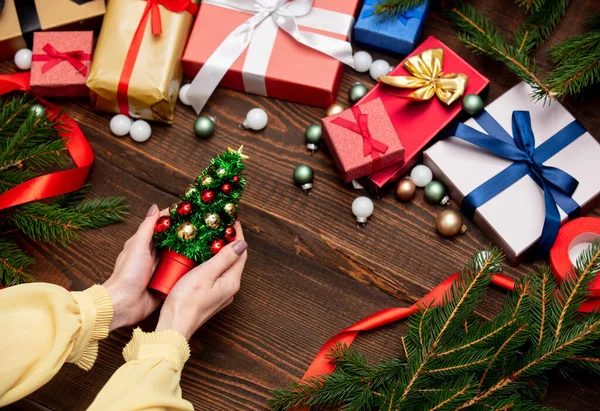 Θηλυκό Χέρι Κρατά Χριστουγεννιάτικο Δέντρο Κοντά Χριστουγεννιάτικα Δώρα Και Κλαδιά — Φωτογραφία Αρχείου