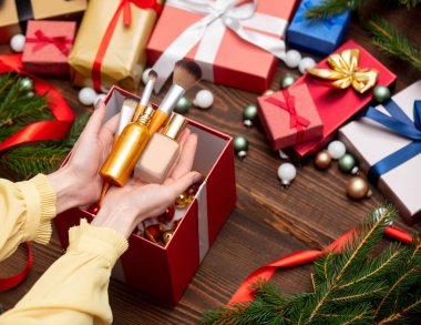 Kadın eli kozmetik ürünlerini Noel hediyelerinin yanında tutuyor