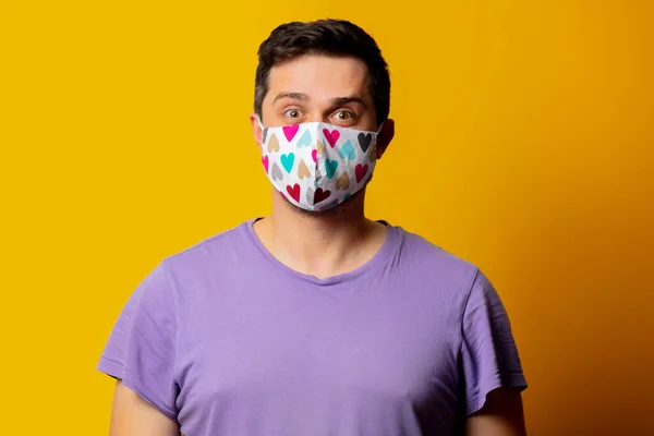 stock image style guy in face mask and purple t-shirt on yellow background