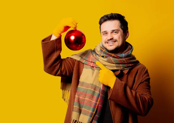 Stijl Man Jas Sjaal Met Kerstbal Gele Achtergrond — Stockfoto