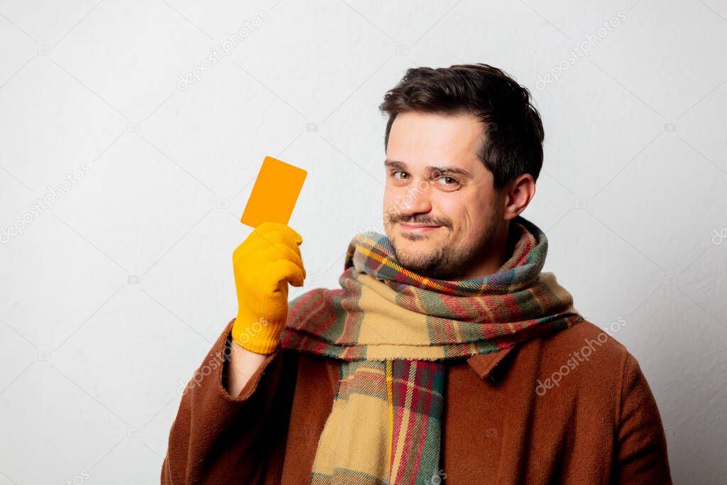 Style man in coat and scarf with card on white background