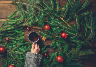 Masada Noel ağacı olan kadın elleri çay bardağını tutuyor. 