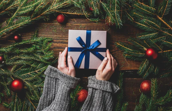 Kadın Eli Hediye Kutusunu Noel Süslemesinin Yanında Bir Masanın Üzerinde — Stok fotoğraf