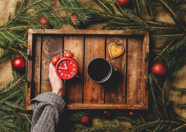 女性の手は トレイにお茶とクリスマスツリーのカップの横に目覚まし時計を保持します — ストック写真