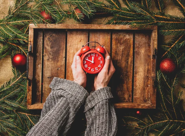 女性の手は クリスマスの装飾の横にトレイに目覚まし時計を保持 — ストック写真