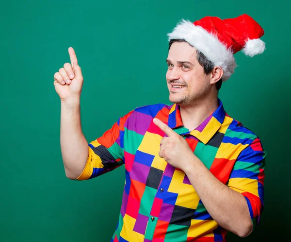 Guy in Christmas hat and vintage shirt on green background