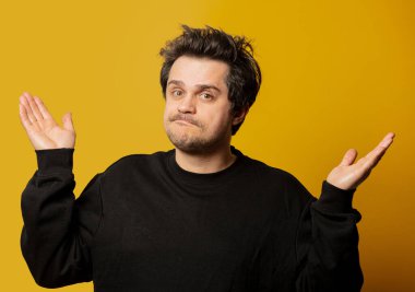 Sarı arka planda siyah gömlekli beyaz adam şaşırdı. 