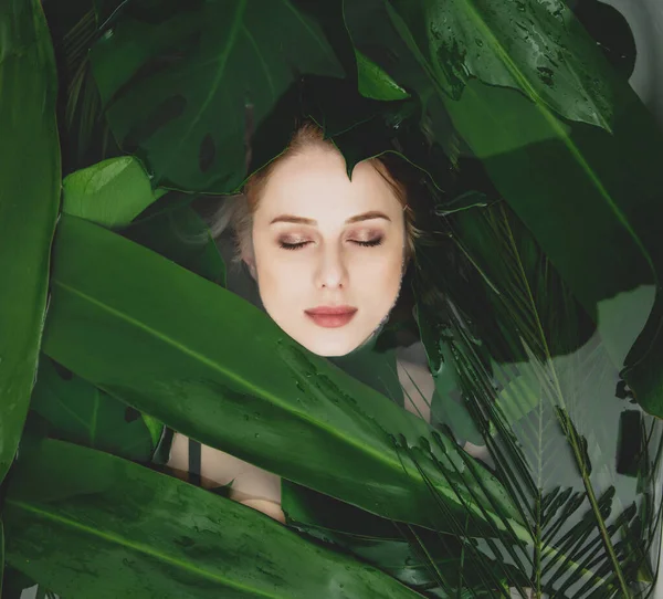 美しい白い女性は周りのヤシの葉とバスタブに横たわっています — ストック写真