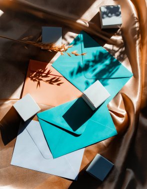 Gölgeli altın kumaş üzerinde klasik zarflar ve küpler.