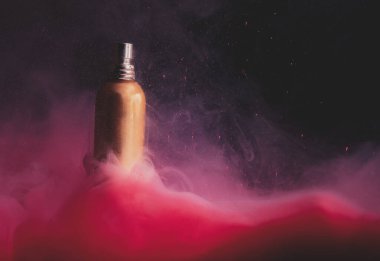 Su altında kırmızı bir boyada altın parfüm şişesi