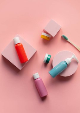 çok renkli şişeler ve pembe arka planda diş fırçası olan kavanoz