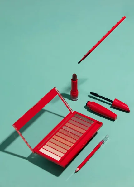 Cosmetic kit, pencil, lipstick, brush and eye shadows on blue background