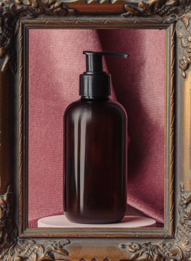 Dark bottle in photo frame on burgundy color fabric background 