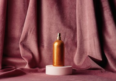 Golden perfume bottle and burgundy color fabric on background 