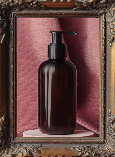 Dark bottle in photo frame on burgundy color fabric background 