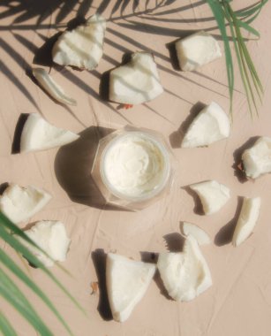 Hindistan cevizi ve krema kavanozda, masada palmiye yaprakları var. Üst görünüm 