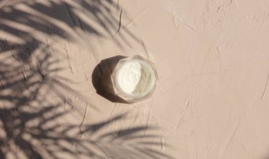 Kokteyl kremalı kavanoz ve kahverengi arka planda aynı ağaç yaprakları. Üst görünüm 