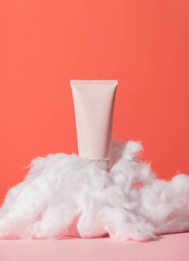 Kozmetik tüp ve turuncu ve pembe arka planda dolanıyor.