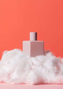 Kozmetik şişesi ve turuncu ve pembe arka planda dolanıyor.