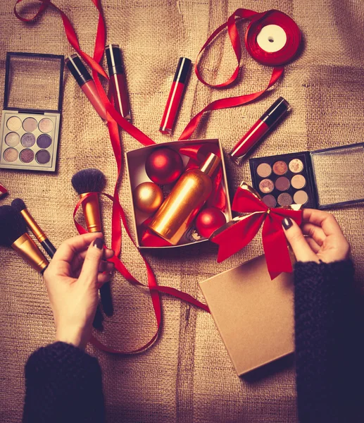 hands are wrapping cosmetics in christmas gifts