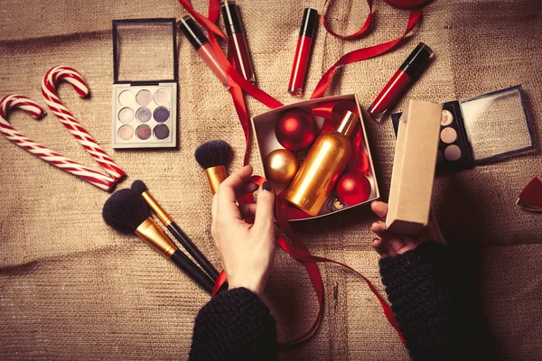 Руки заворачивают косметику в рождественские подарки — стоковое фото