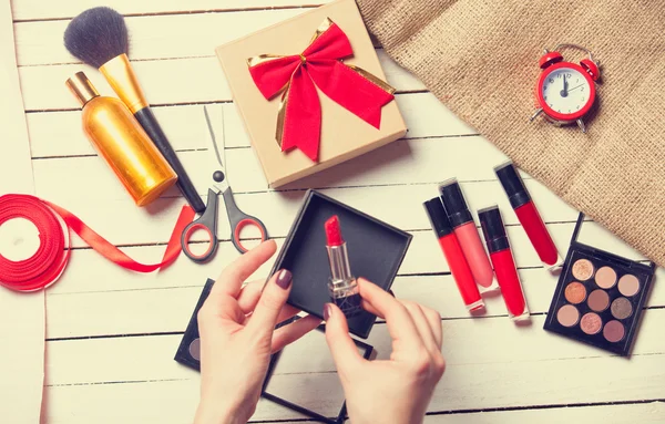 Hands wrapping cosmetics in christmas gift — Stock Photo, Image