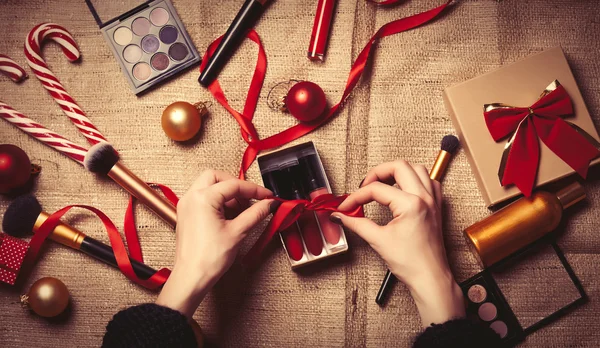 Les mains enveloppent les cosmétiques dans des cadeaux de Noël — Photo