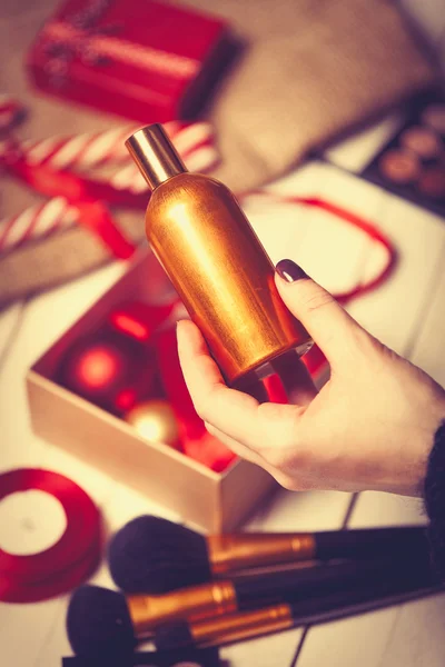 Рука заворачивает косметику в рождественские подарки — стоковое фото
