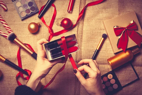 Les mains enveloppent les cosmétiques dans des cadeaux de Noël — Photo