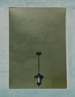 Evin tavanında asılı duran antika lamba. Ön duvarda da kutu çerçevesi var.