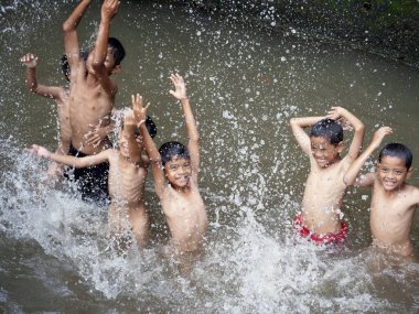 Erkekler 2 Ocak 2026 'da Endonezya' nın Jakarta şehrinde nehirde su sıçratıyor.
